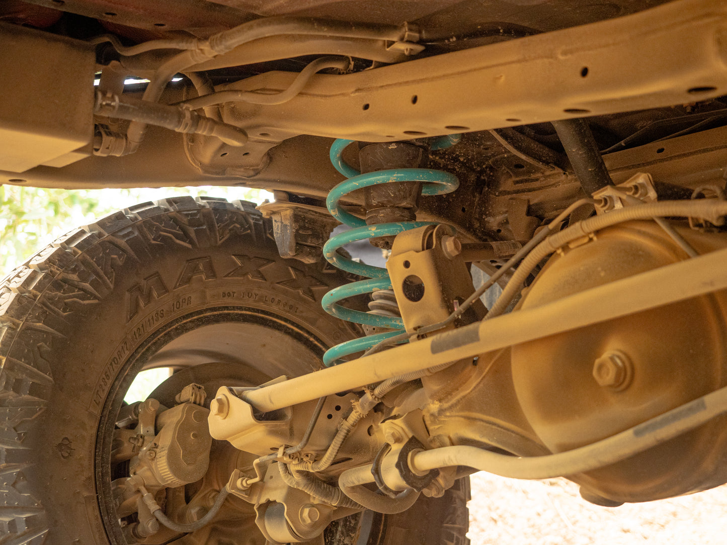 Underbody view of GWM Tank 300 suspension flex, showing Dobinsons shocks and coil articulation.